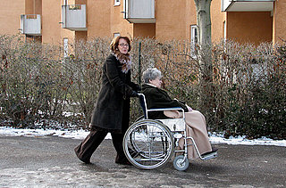 Frau im Rollstuhl wird von einer anderen Frau geschoben